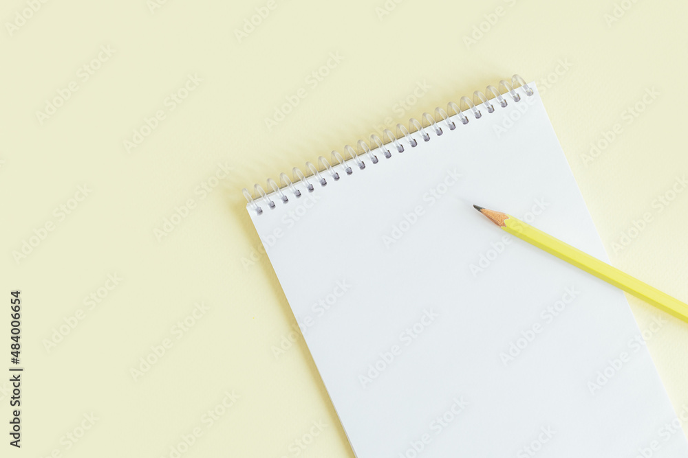 Notebook with blank page and pencil on a yellow pastel background. Notebook with blank page and pencil on a yellow pastel background.