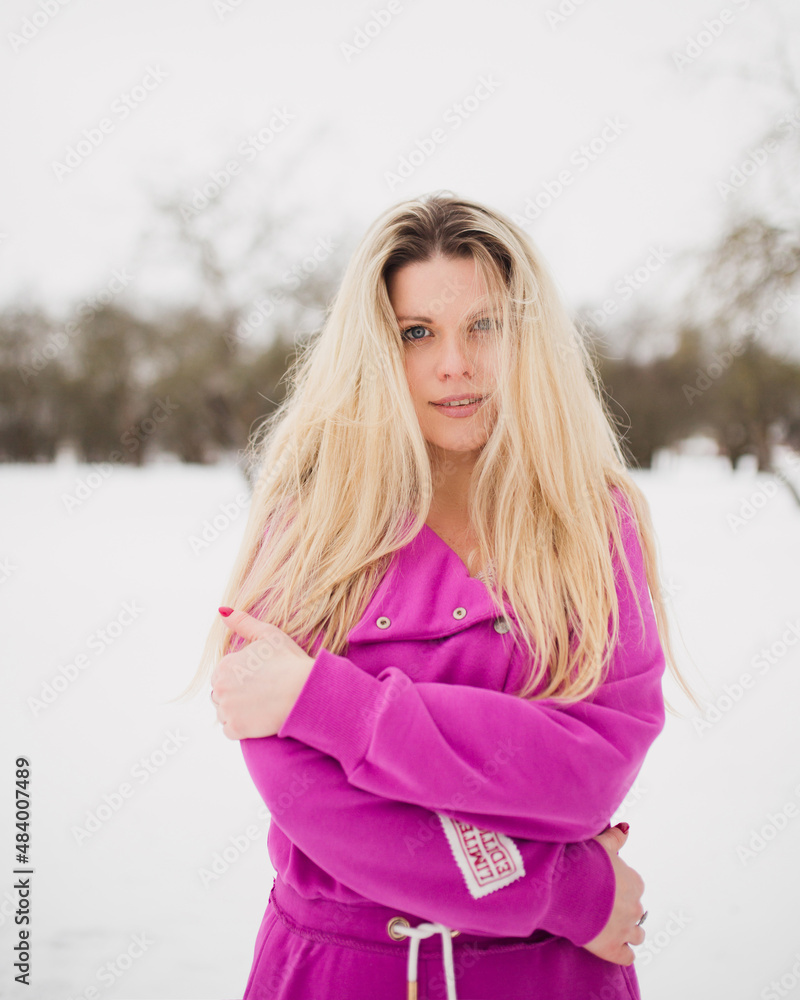 Playful smile on the face of a charming blonde on a winter day in the park - romantic mood on the face of a happy woman in love Playful smile on the face of a charming blonde on a winter day in the park - romantic mood on the face of a happy woman in love