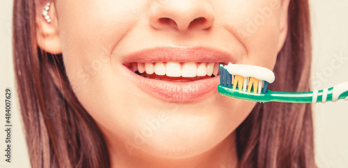 Dental health background. Close up of perfect and healthy teeth with toothbrush. Portrait of a smiling cute woman holding toothbrush. Smiling woman with healthy beautiful teeth holding a toothbrush