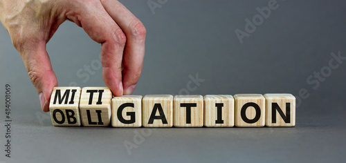 Obligation and mitigation symbol. Businessman turns wooden cubes changes the concept word obligation to mitigation. Beautiful grey background copy space. Business obligation and mitigation concept. photo