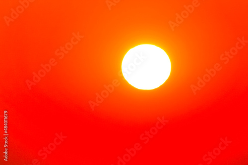 View of the bright white sun in the red sky over hot country.