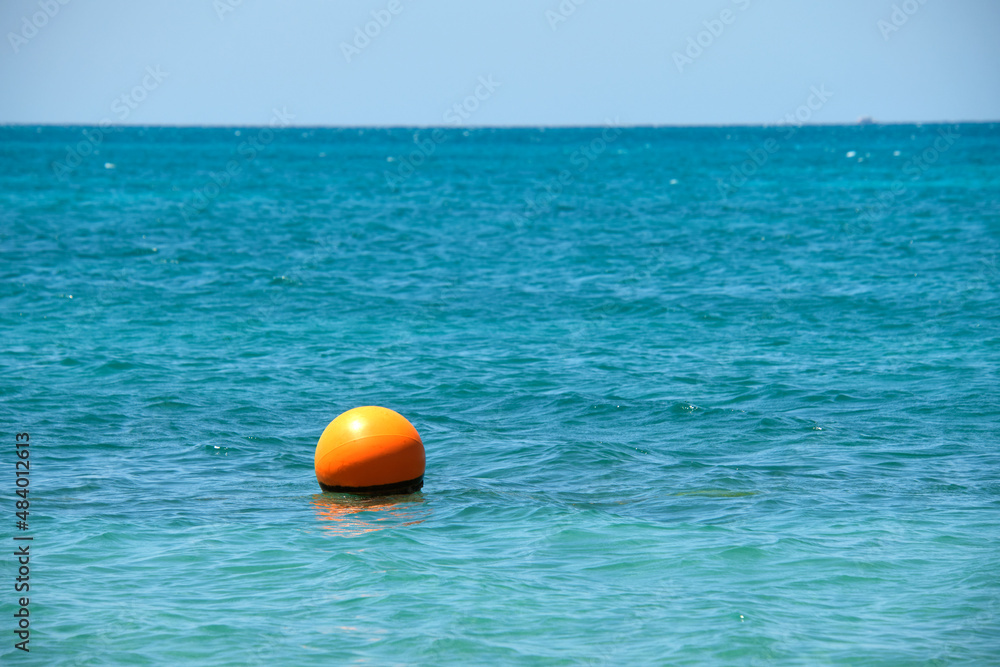 Orange buoy floating on sea surface waves. Human life safety concept