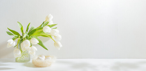 White spring tulips in a vase, easter eggs on a white table. Mock up for displaying works