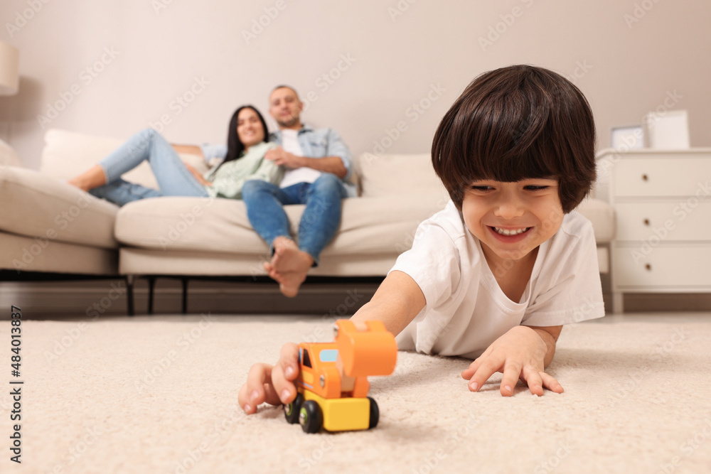 Child playing with toy and parents working at home Child playing with toy and parents working at home
