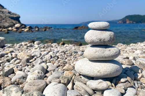 Closeup view of sea pebbels tower on the beach against blue sea and sky as background - symbol of energy and life balance photo