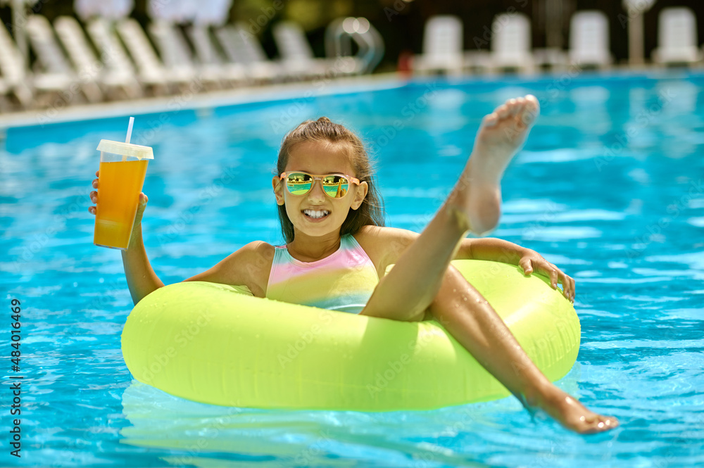 Girl on inflatable circle on water raising leg