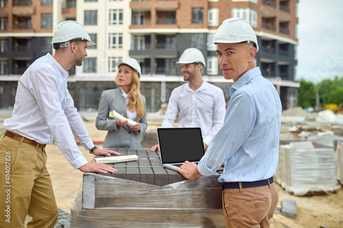 Builder standing among his three colleagues on the building site