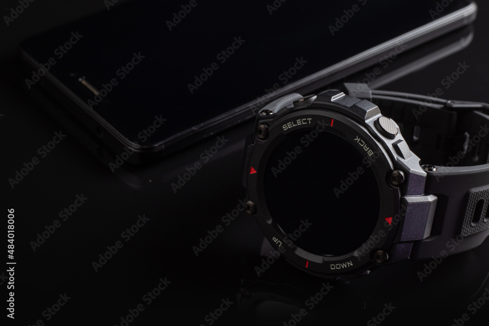 Black smart watch on the smartphone. Closeup, selective focus Black smart watch on the smartphone. Closeup, selective focus