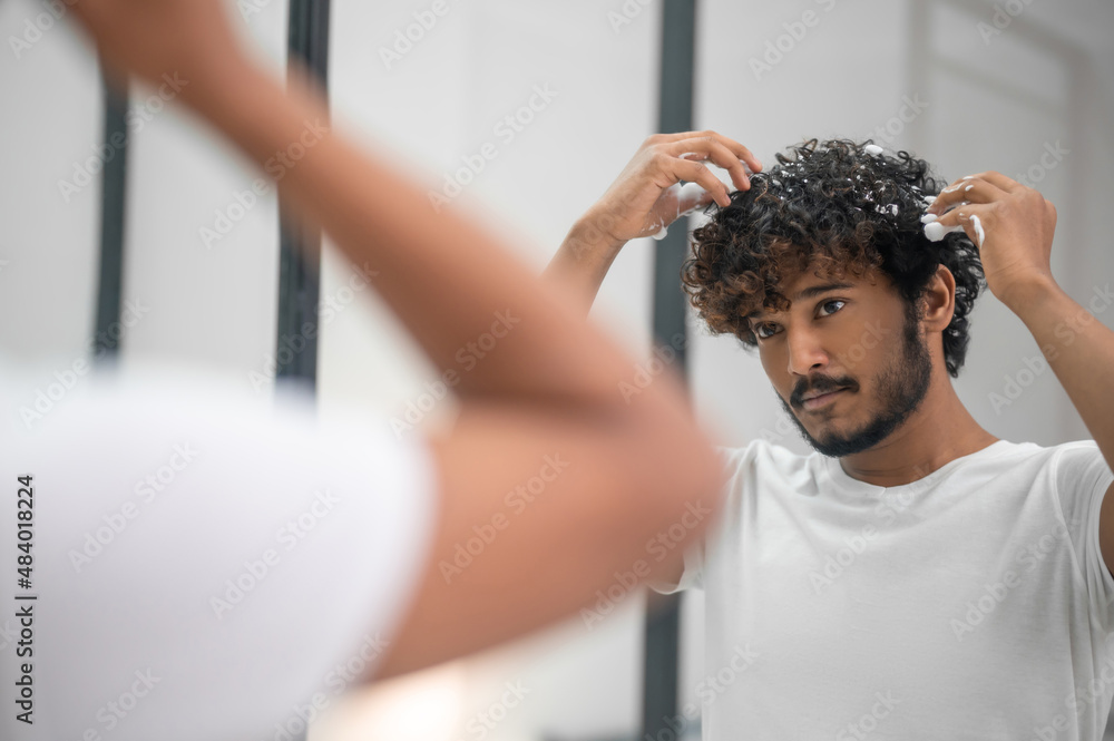 Male rubbing the hairstyling product into his curls Male rubbing the hairstyling product into his curls