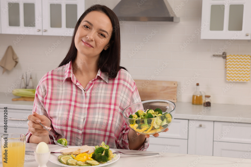Beautiful overweight woman having healthy meal at table in kitchen Beautiful overweight woman having healthy meal at table in kitchen