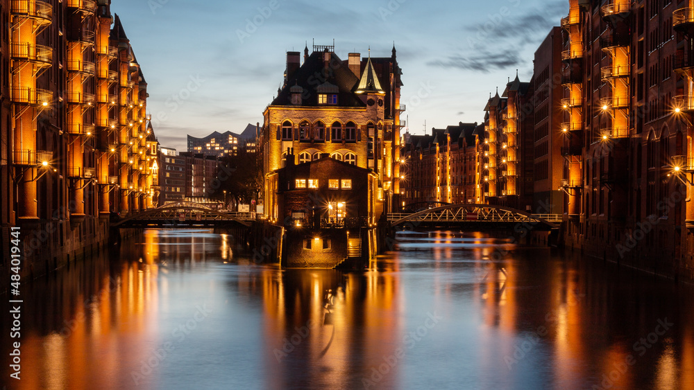 Moated castle in the Speicherstadt illuminated in the evening. Moated castle in the Speicherstadt illuminated in the evening.
