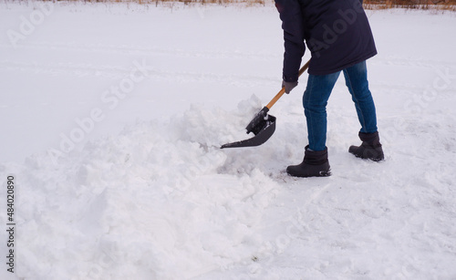 A man cleans snow from the sidewalk after a blizzard, snowfall. A man cleans the snow in the yard.