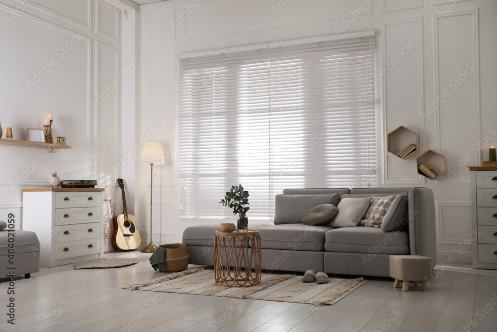 Fototapeta premium Living room with comfortable grey sofa and stylish interior elements near window