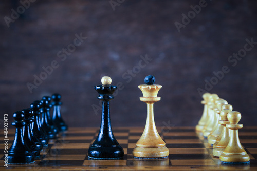 Black and white knight on a chessboard on a wooden background. Competition and victory concept. Cold light. 