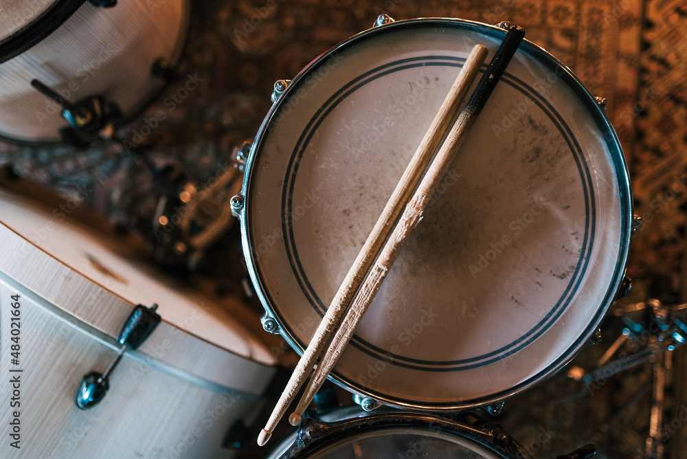 Fototapeta premium From above of worn out wooden drumsticks placed on drum on stage for rehearsal