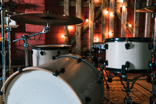 Drum set placed on carpet on stage decorated with shining garland for music concert in bar