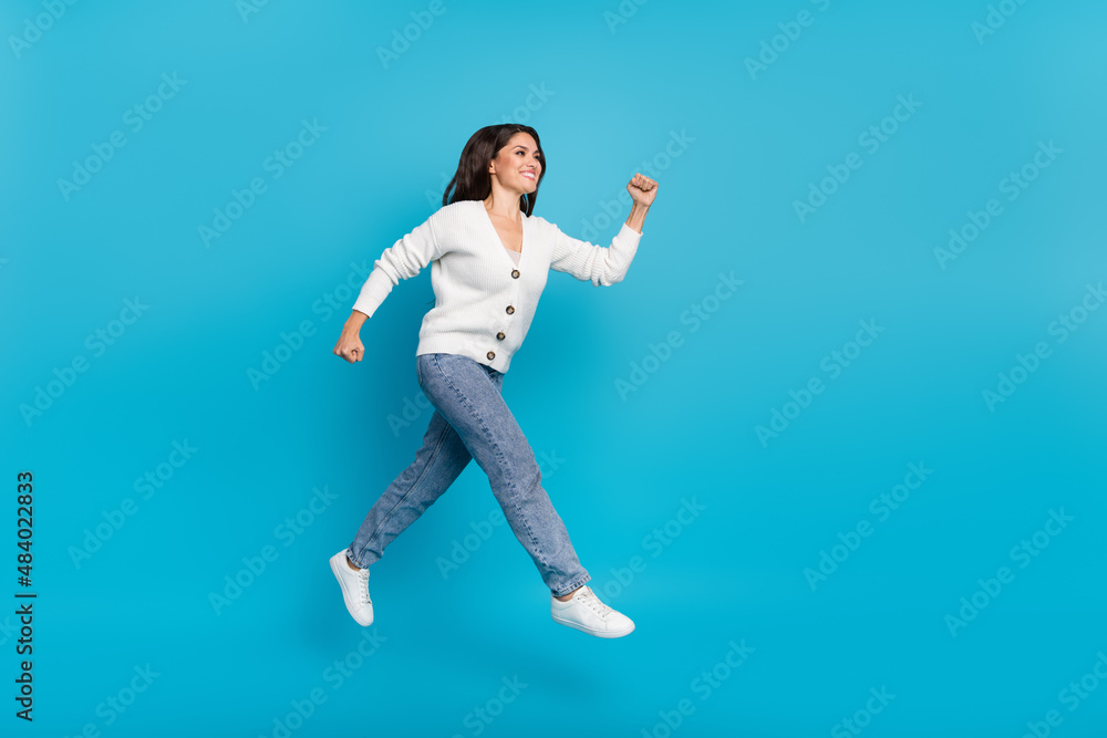Photo of shiny pretty lady dressed white cardigan jumping high running fast isolated blue color background