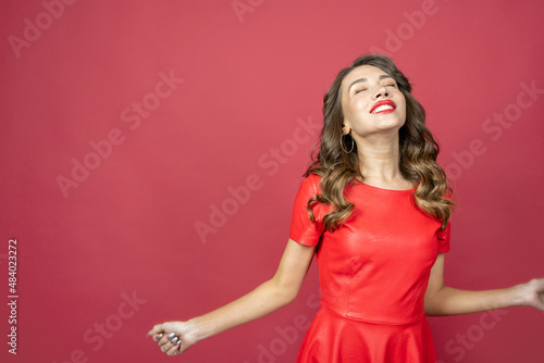 Joyful brunette woman in red dress on a red background