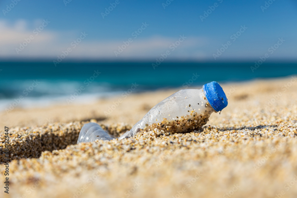 Garbage pollution of the planet. Empty plastic bottle on the beach sand. Consequences of human life Garbage pollution of the planet. Empty plastic bottle on the beach sand. Consequences of human life
