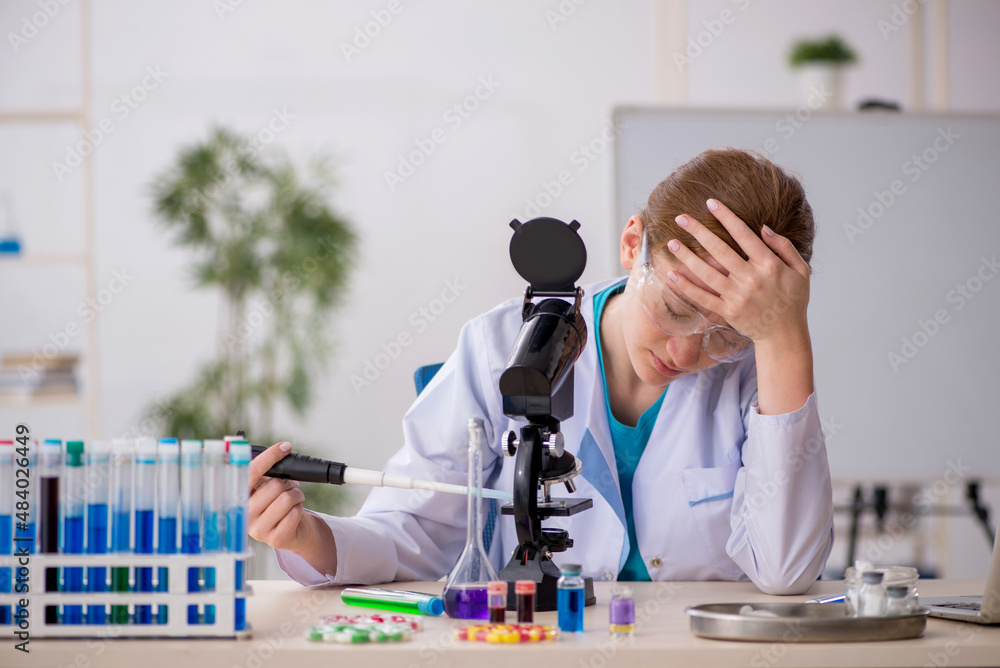 Naklejka premium Young female chemist in drugs synthesis concept