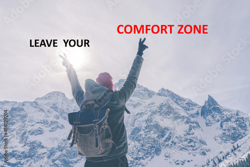 Leave your comfort zone. Person from behind with hands up in mountains. Motivation call to action photo
