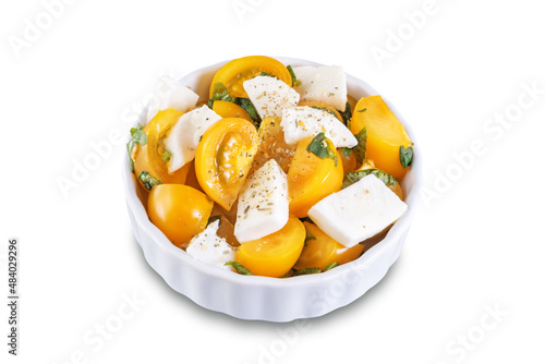 Yellow tomatoes basil pepper mozarella salad in a bowl on a white isolated background