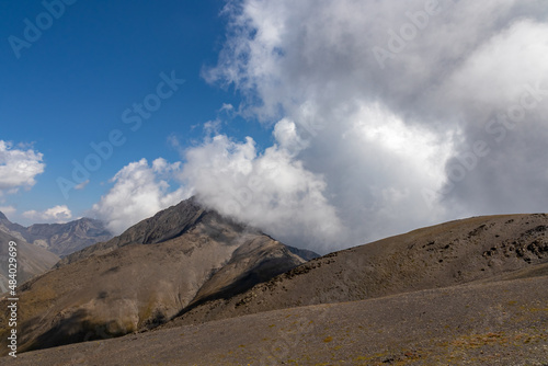 Clouds accumulating around the sharp mountain peaks of the Chaukhi Pass in the Greater Caucasus Mountain Range in Georgia, Kazbegi Region. Mountain Ridges, Hiking. Georgian Dolomites. Cloudscape © Chris