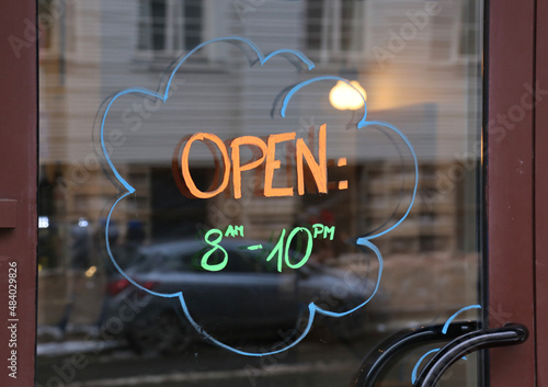 Opening hours written on glass window of the restaurant or shop