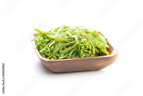 Green wakame. Seaweed salad in wooden bowl isolated on white background.