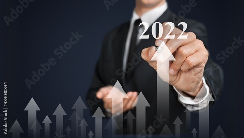 Businessman in a suit chooses 2022 on a background. new year start ideas