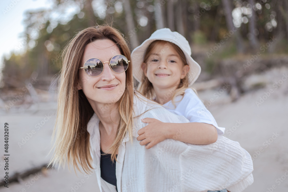 Obraz premium Mother having daughter a piggyback at the beach. Have fun together.
