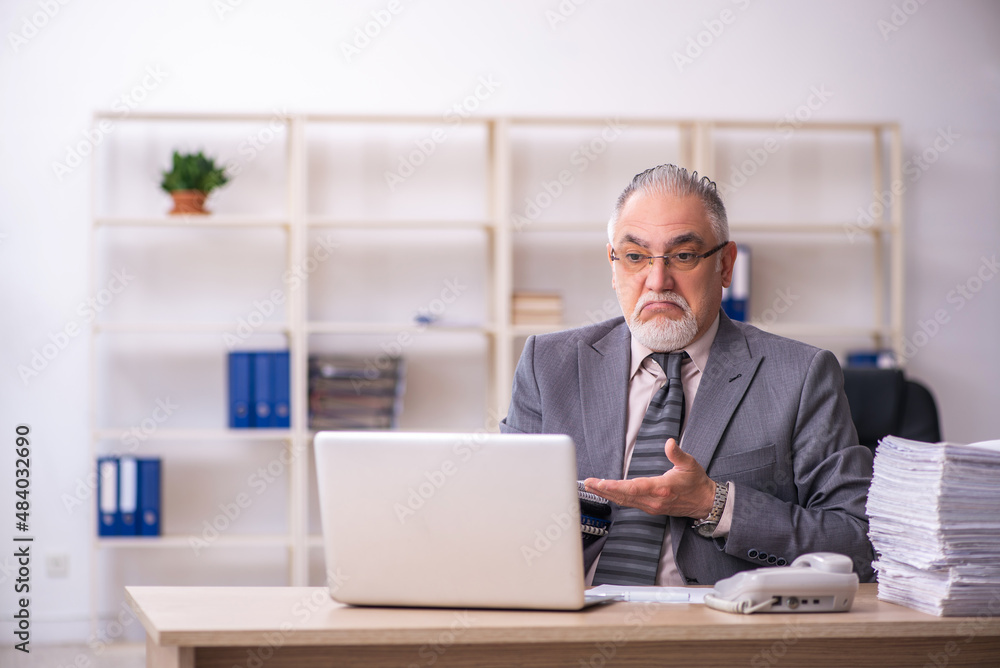 Old male employee working at workplace Old male employee working at workplace