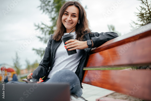 Woman girl using a computer, laptop, working remotely in the park. Distance learning online-education and work.