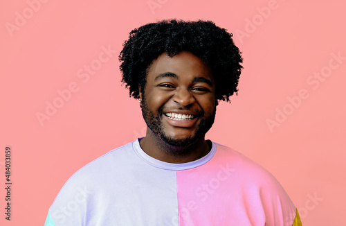 closeup portrait young happy man smiling looking at the camera in the studio over pink background