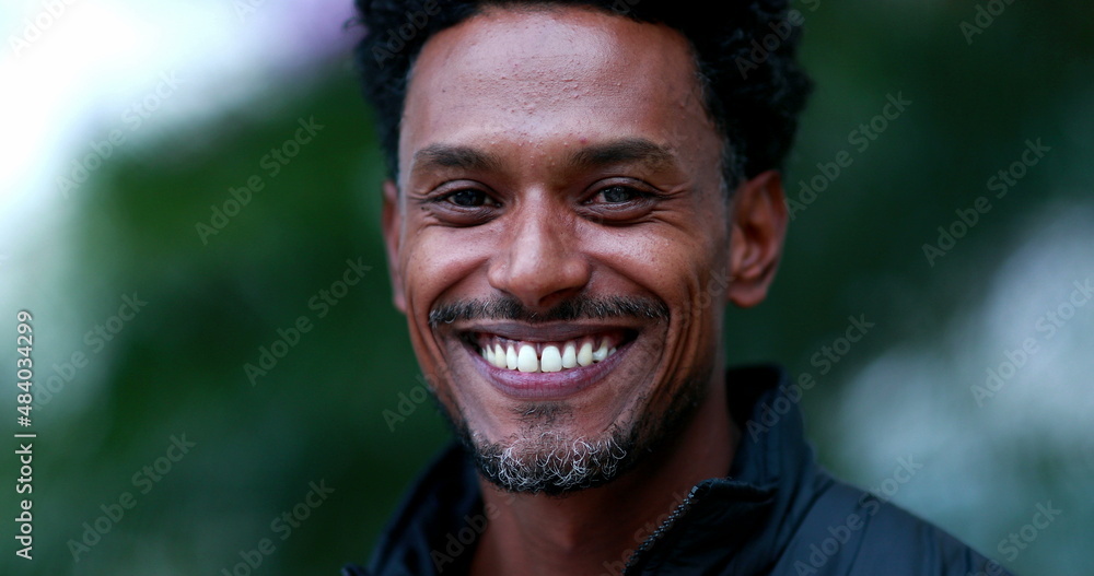 Portrait of mixed race man smiling to camera. Friendly happy african american descent person face outdoors Portrait of mixed race man smiling to camera. Friendly happy african american descent person face outdoors