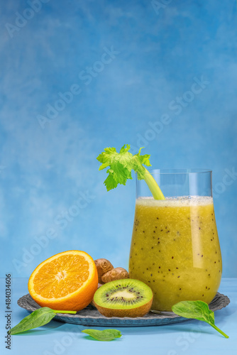 Glass of green spinach, orange, ginger and kiwi healthy smoothies.