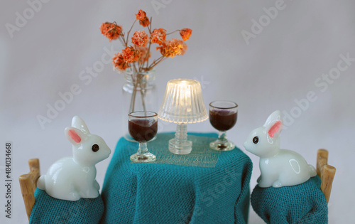 Couple of toy white rabbits on a romantic date drinking wine. Funny and ironic Saint Valentines day postcard