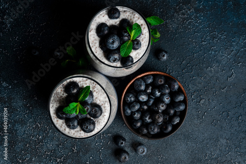 Chia pudding with blueberries on a dark background. Chia pudding, mint and blueberries on a black background.