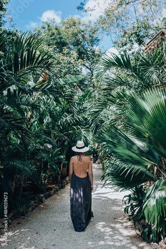 Girl in a luxury boutique hotel. Woman in sundress and hat walking in tropical jungle photo