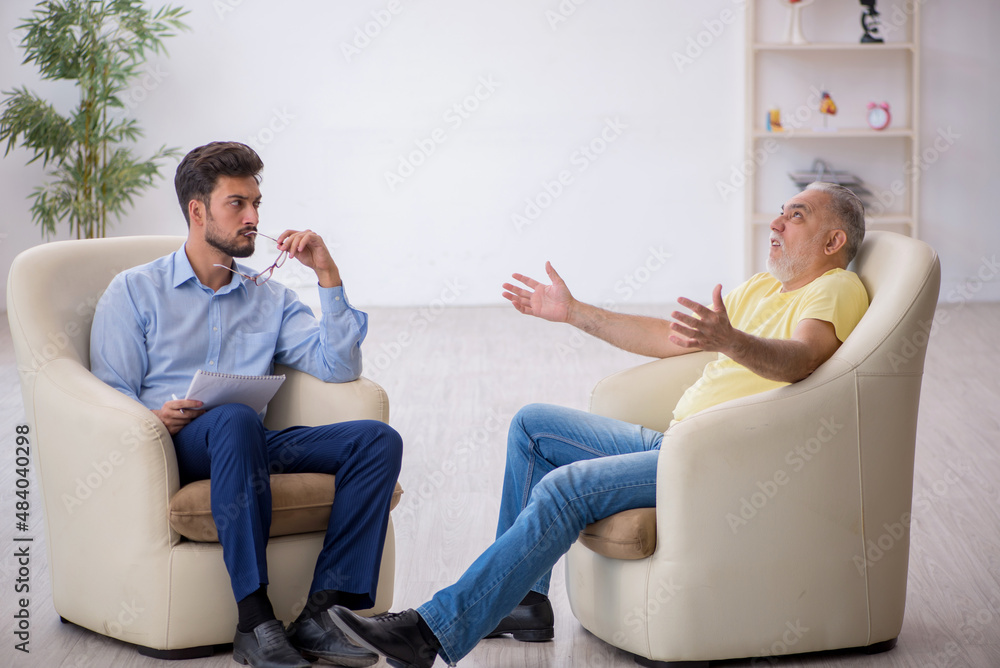 Old man visiting young male psychotherapist Old man visiting young male psychotherapist