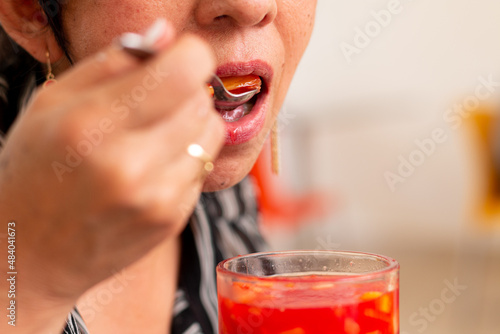 Unknown adult female eating unblended red fruit drink. Tropical and delicious fruits. Colombian woman enjoying a typical Colombian meal of tropical fruits. Salpicon
