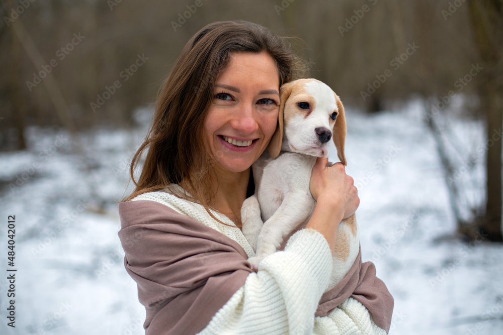 woman in scarf hugs with cute beagle puppy in the snowy winter forest woman in scarf hugs with cute beagle puppy in the snowy winter forest