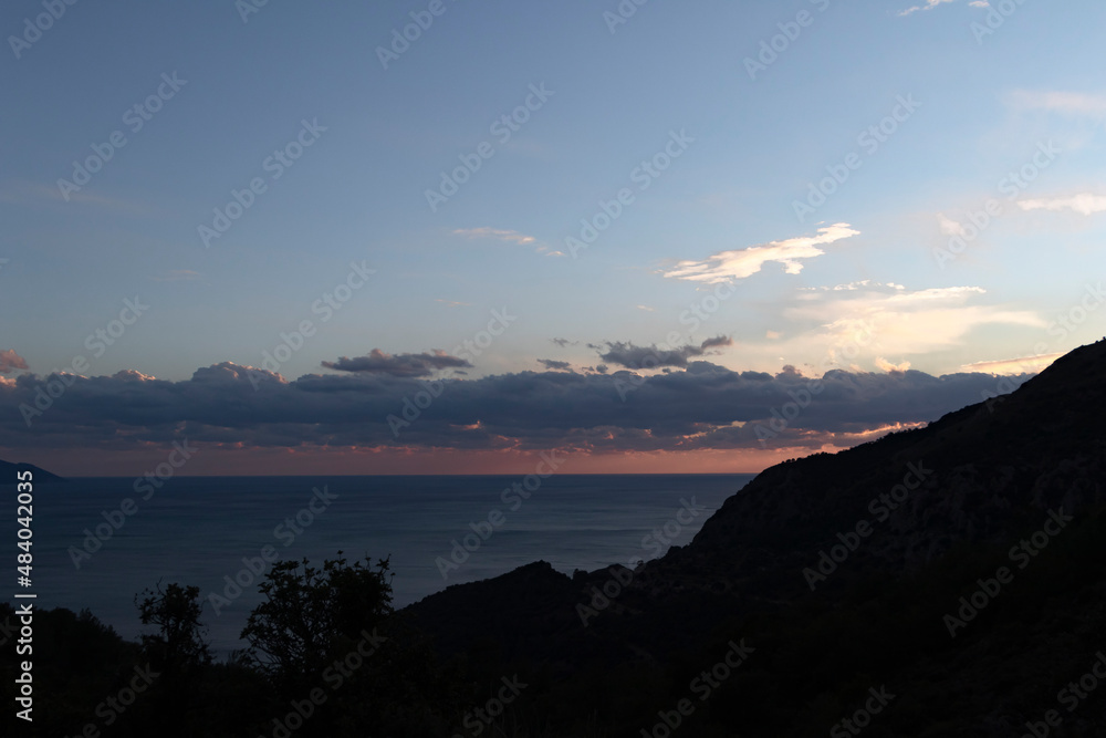 Spectacular light on top of the mountain. Sea, horizon and cloudy blue sky. Sun lights.	
