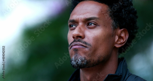 Candid pensive man thinking outdoors. Thoughtful mixed race african descent person standing outside