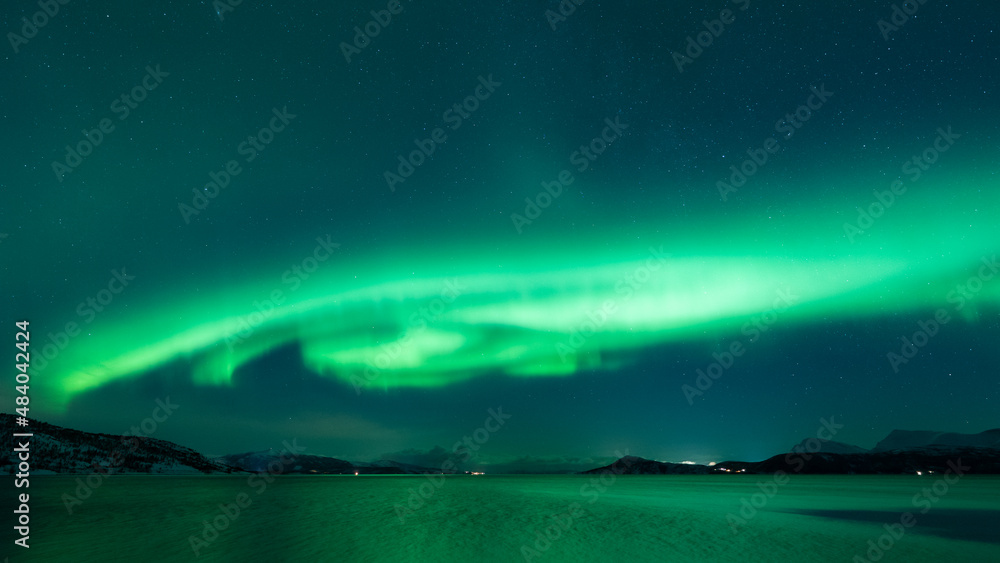 Ufo shaped aurora hovering over the arctic fjord in the north, reflecting in the water