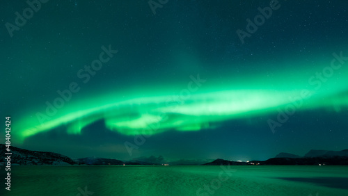 Ufo shaped aurora hovering over the arctic fjord in the north, reflecting in the water