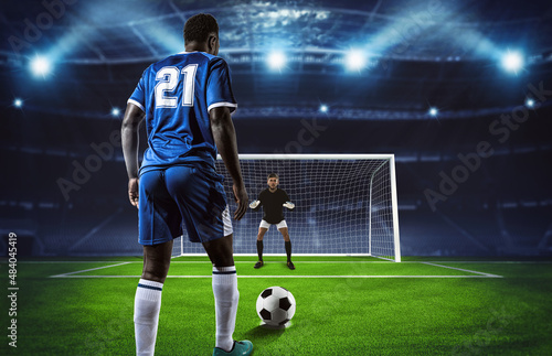 Soccer scene at night match with player in blue uniform kicking the penalty kick © alphaspirit