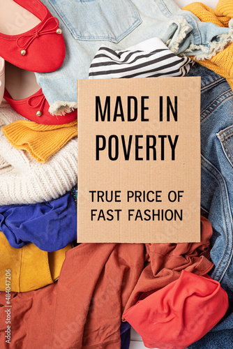 Fast fashion background with pile of cheap, low quality clothes. Garment made in unjust, inhumane conditions idea. Environmental impact, carbon emissions concept