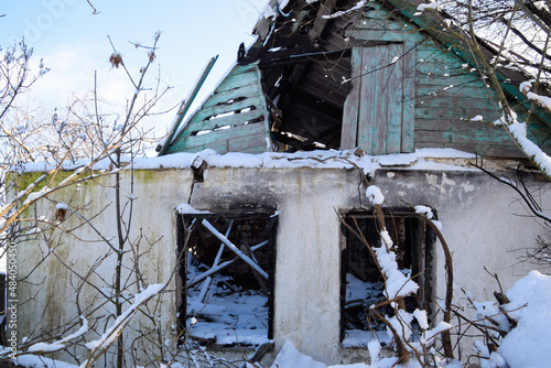 Old ruined house in the village in winter. Snow in yard. photo