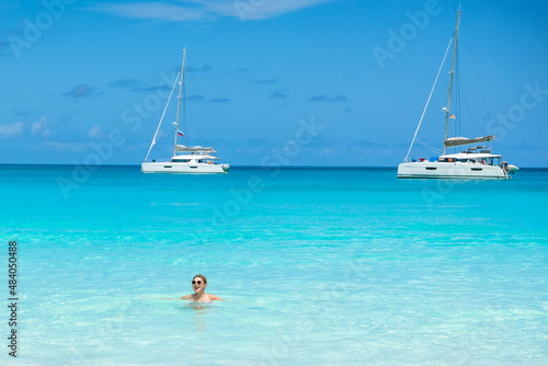 Woman enjoying vacation swims in the ocean near the yachts